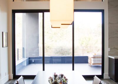 Modern dining room with a rectangular wooden table, surrounded by chairs, and a large pendant light above.