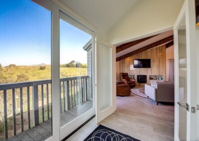Open balcony door in a modern living room with a view of rolling hills.