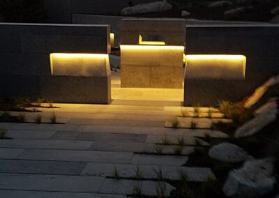 Lighted modern staircase descending between walls at twilight.