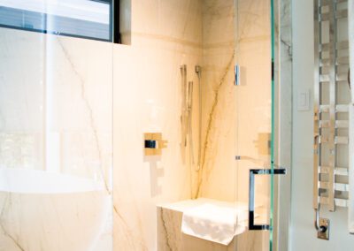 Modern bathroom with marble walls and glass shower enclosure.