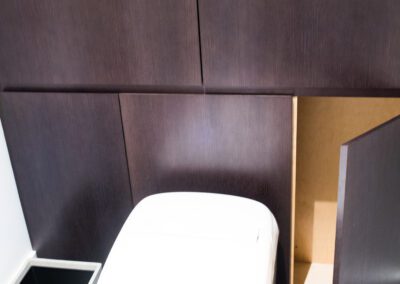 A modern bathroom with a wall-mounted toilet and dark wood cabinets.