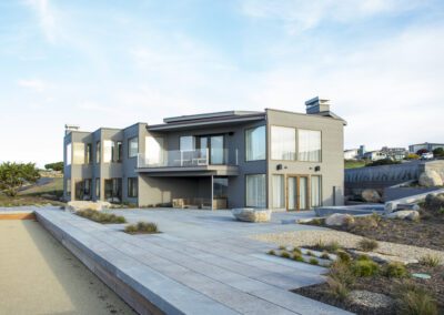Modern two-story house with gray exterior, large windows, and landscaped surroundings.